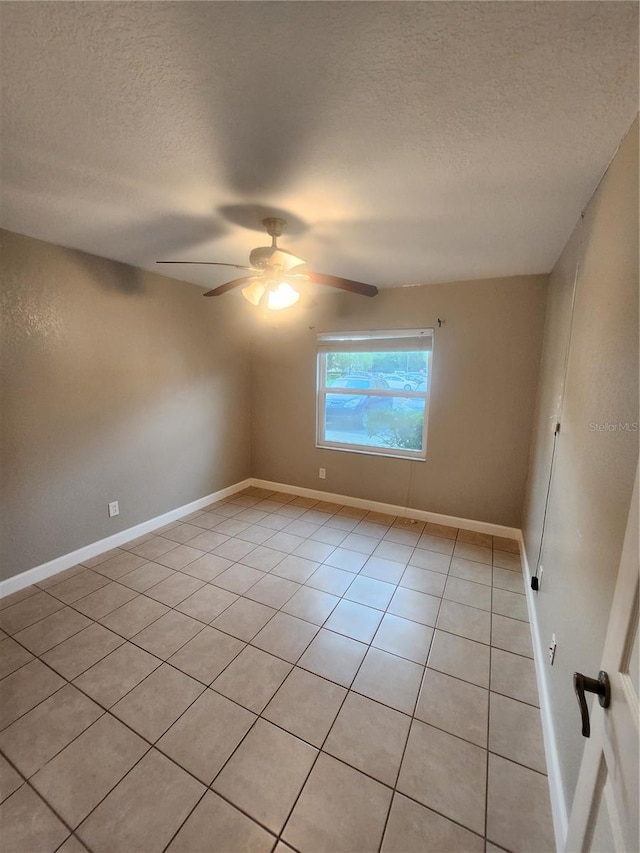 spare room with ceiling fan, a textured ceiling, and light tile patterned floors