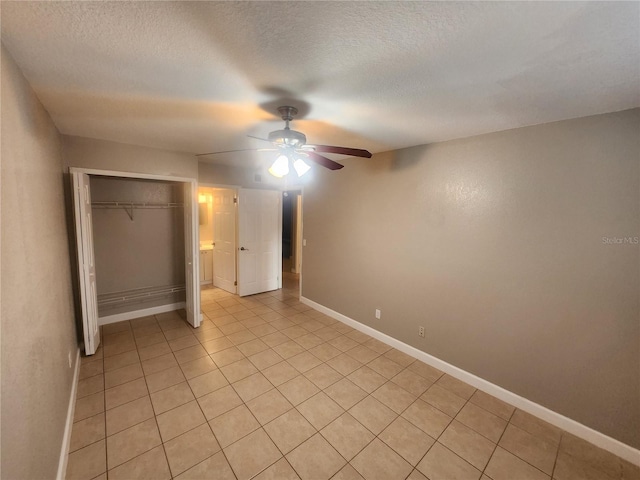 unfurnished bedroom featuring a closet, a textured ceiling, light tile patterned floors, and ceiling fan