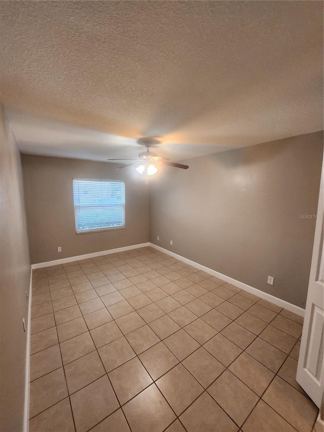 spare room with ceiling fan, a textured ceiling, and light tile patterned floors