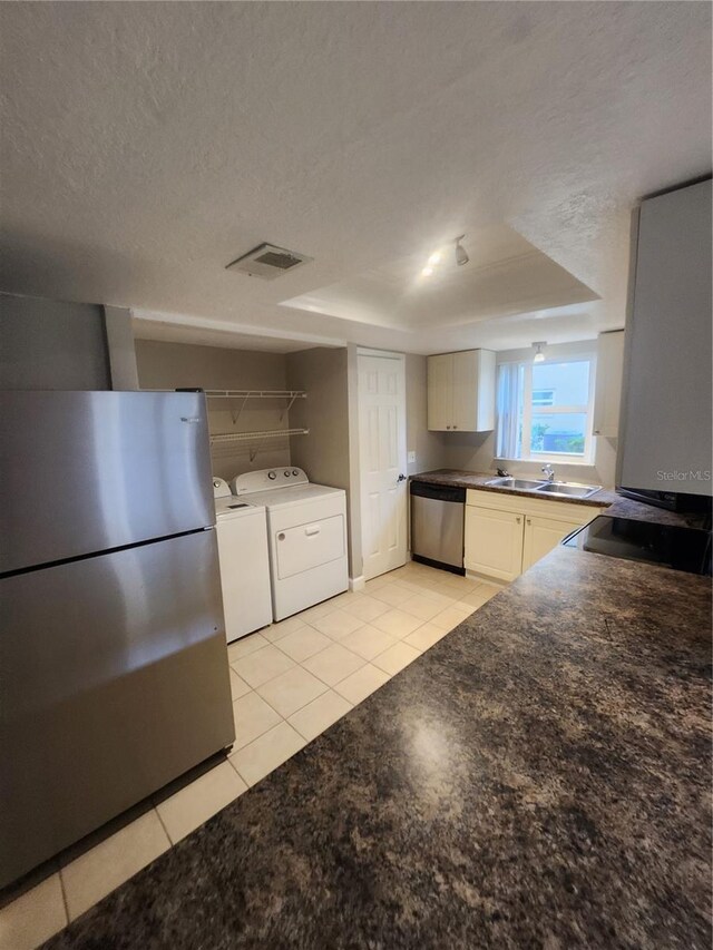 kitchen with light tile patterned flooring, a textured ceiling, stainless steel dishwasher, and washing machine and clothes dryer