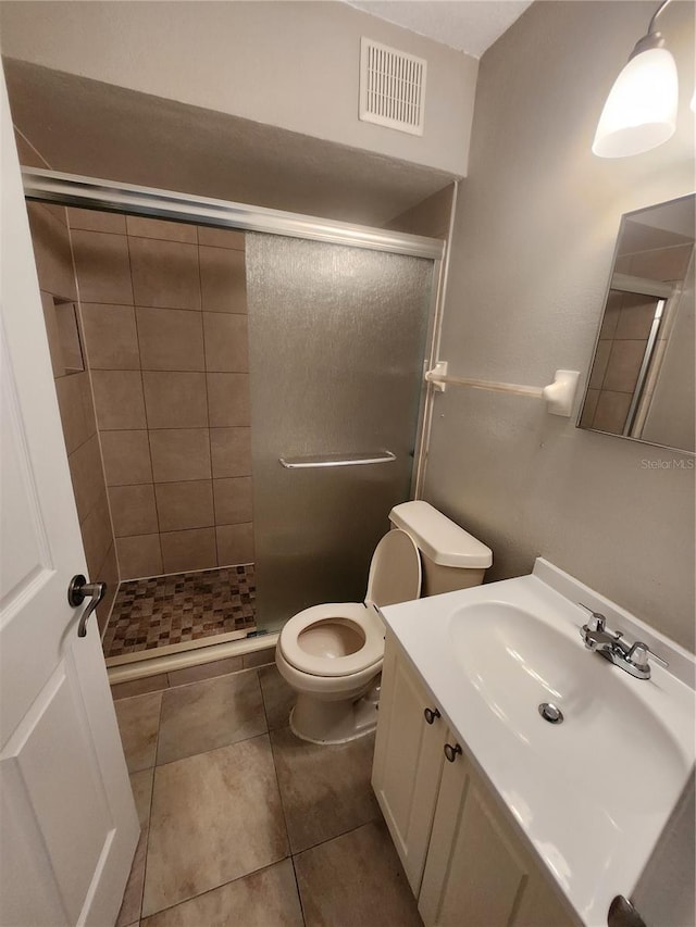 bathroom featuring vanity, toilet, walk in shower, and tile patterned flooring