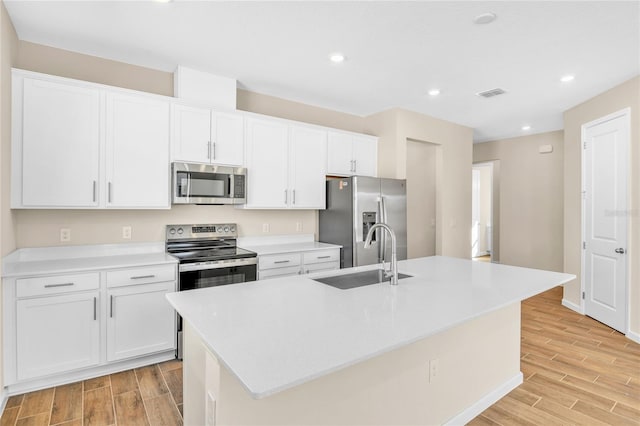 kitchen featuring white cabinetry, stainless steel appliances, sink, and a kitchen island with sink