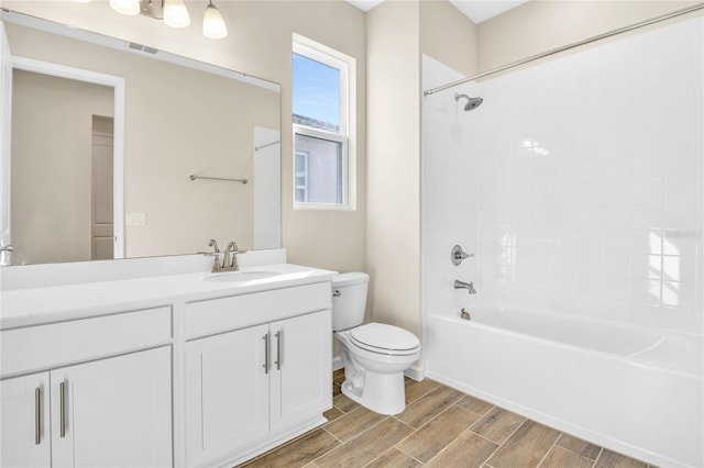 full bathroom featuring tiled shower / bath, vanity, and toilet