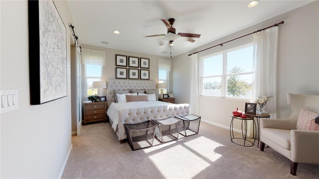 bedroom with a barn door, light carpet, and ceiling fan