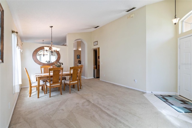 dining space with a notable chandelier, a high ceiling, and light carpet