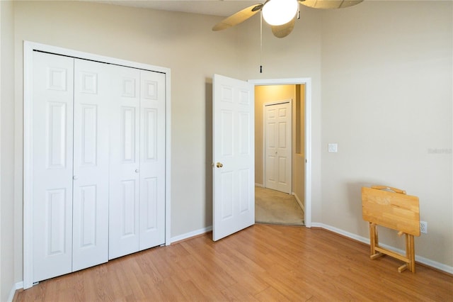 unfurnished bedroom featuring lofted ceiling, a closet, light wood-type flooring, and ceiling fan