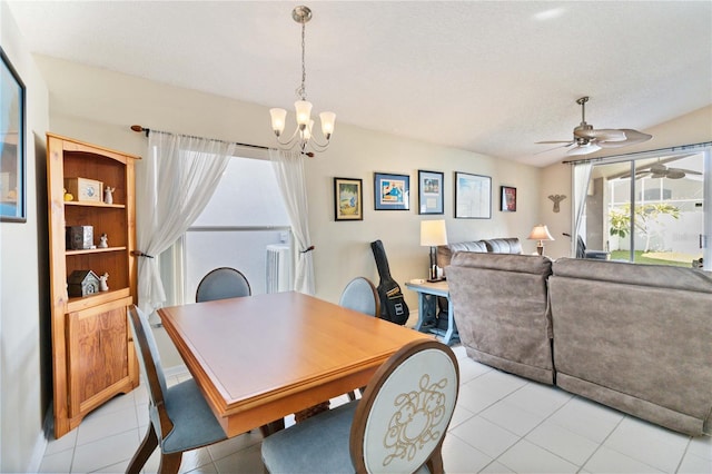 dining area featuring a textured ceiling, light tile patterned flooring, and ceiling fan with notable chandelier