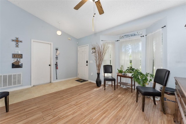 sitting room featuring lofted ceiling, a textured ceiling, light wood-type flooring, and ceiling fan