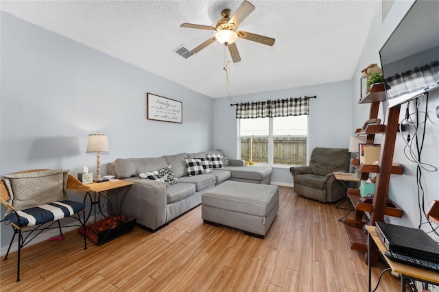 living room with light hardwood / wood-style flooring, a textured ceiling, and ceiling fan