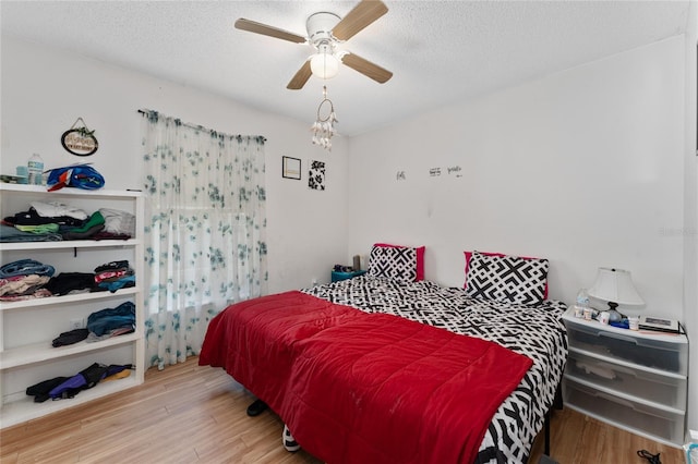 bedroom with a textured ceiling, light wood-type flooring, and ceiling fan