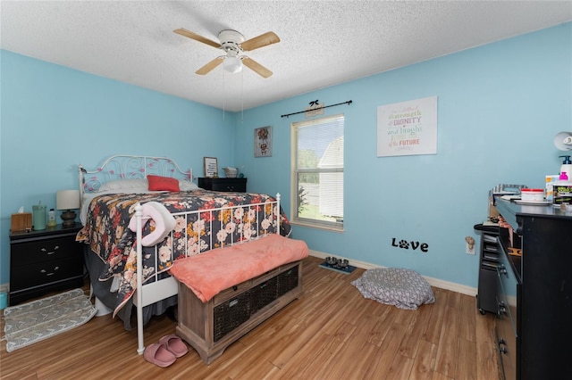 bedroom with a textured ceiling, hardwood / wood-style flooring, and ceiling fan