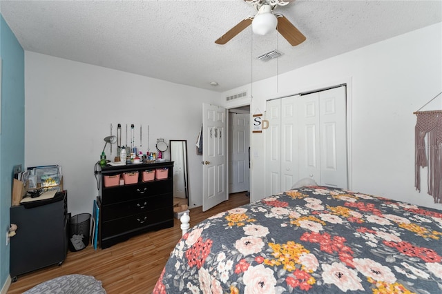 bedroom with a closet, ceiling fan, wood-type flooring, and a textured ceiling