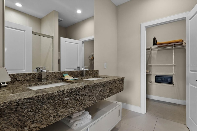 bathroom with a shower with door, vanity, and tile patterned flooring