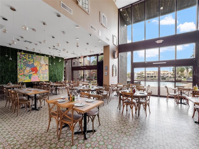 dining space with a water view and a towering ceiling