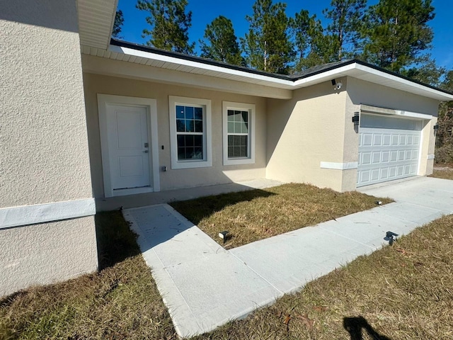 property entrance with a garage and a lawn