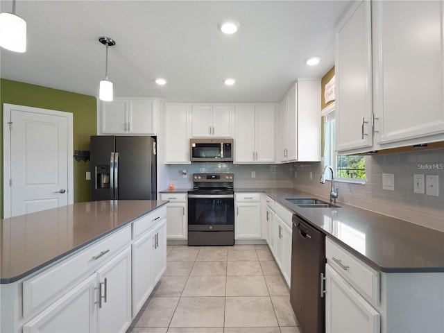 kitchen featuring appliances with stainless steel finishes, a sink, dark countertops, tasteful backsplash, and white cabinets