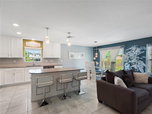 kitchen with a breakfast bar area, white cabinets, a kitchen island, and pendant lighting