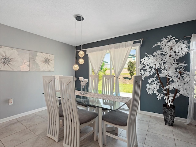 dining area with light tile patterned floors, baseboards, and a textured ceiling