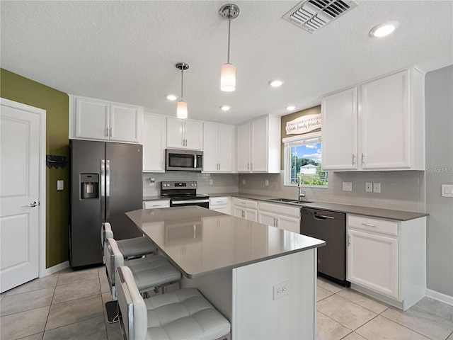 kitchen featuring a kitchen island, appliances with stainless steel finishes, white cabinetry, pendant lighting, and sink