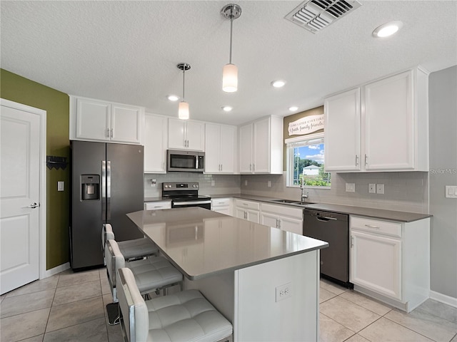 kitchen with stainless steel appliances, a sink, tasteful backsplash, white cabinetry, and a textured ceiling