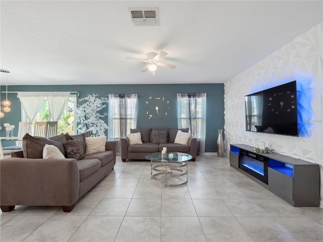 tiled living room with ceiling fan, a textured ceiling, and plenty of natural light