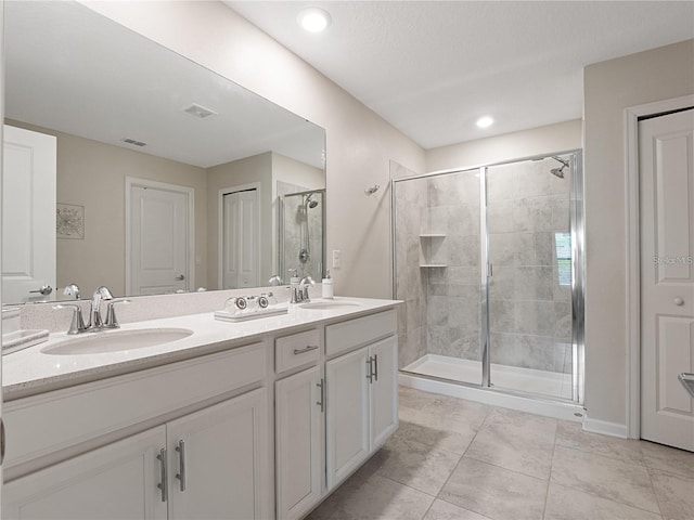 bathroom featuring a stall shower, double vanity, and tile patterned floors