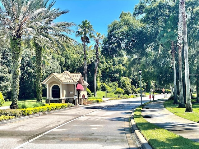 view of asphalt road with street lights, curbs, and sidewalks