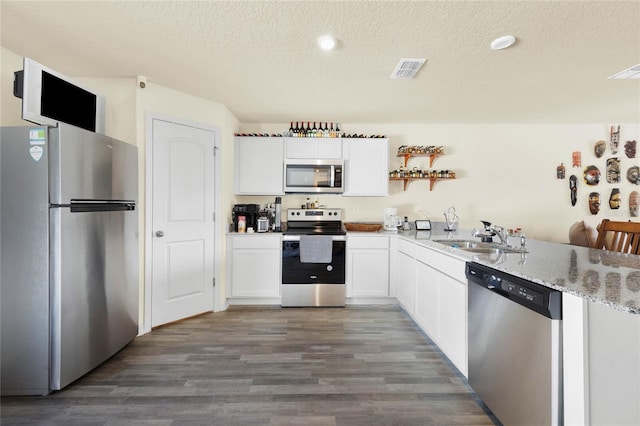 kitchen with appliances with stainless steel finishes, sink, a textured ceiling, dark hardwood / wood-style flooring, and white cabinetry