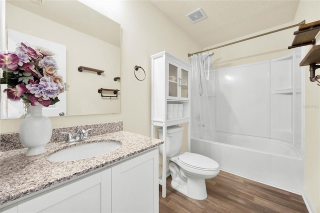 full bathroom featuring toilet, shower / tub combo, hardwood / wood-style floors, vanity, and a textured ceiling