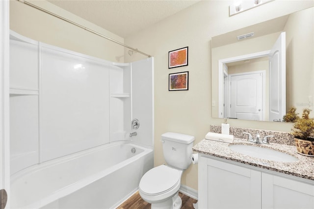 full bathroom with  shower combination, a textured ceiling, hardwood / wood-style floors, toilet, and vanity