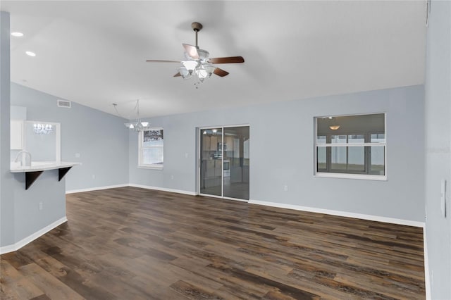 unfurnished living room featuring lofted ceiling, dark hardwood / wood-style floors, and ceiling fan with notable chandelier