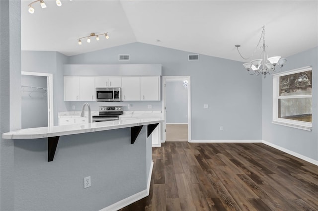 kitchen with dark wood-type flooring, hanging light fixtures, a breakfast bar, white cabinetry, and appliances with stainless steel finishes