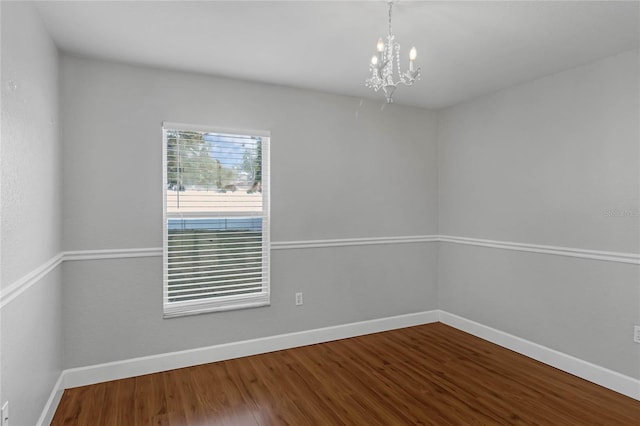 spare room featuring wood-type flooring and an inviting chandelier