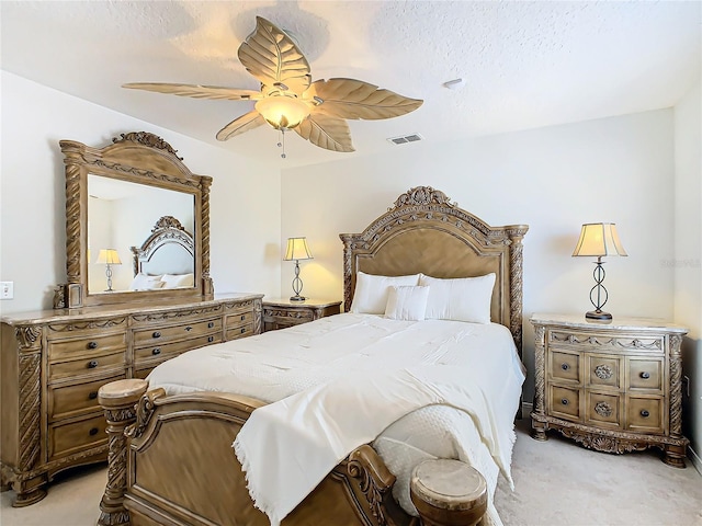 bedroom with ceiling fan, light colored carpet, and a textured ceiling