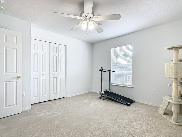 workout room featuring light carpet, a textured ceiling, and ceiling fan