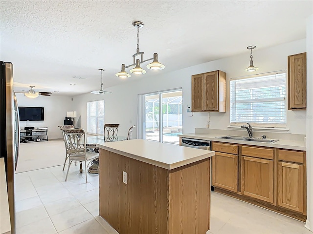 kitchen with a kitchen island, pendant lighting, sink, stainless steel appliances, and a textured ceiling