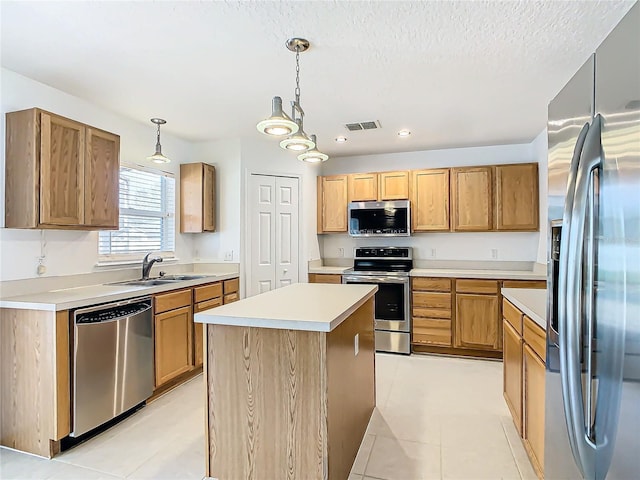 kitchen featuring light tile patterned flooring, sink, decorative light fixtures, appliances with stainless steel finishes, and a kitchen island