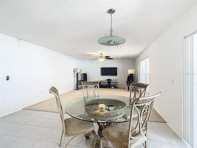 tiled dining space with ceiling fan and a textured ceiling