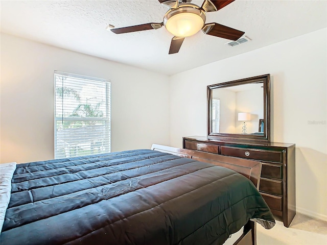 bedroom featuring light carpet, a textured ceiling, and ceiling fan