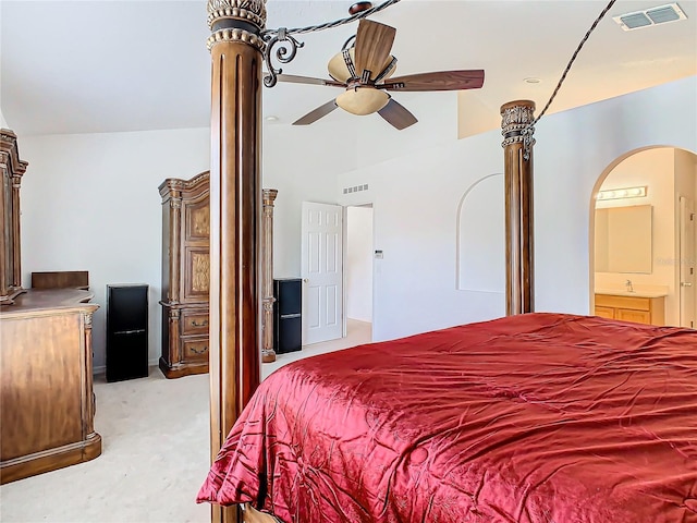 bedroom featuring decorative columns, connected bathroom, and light colored carpet