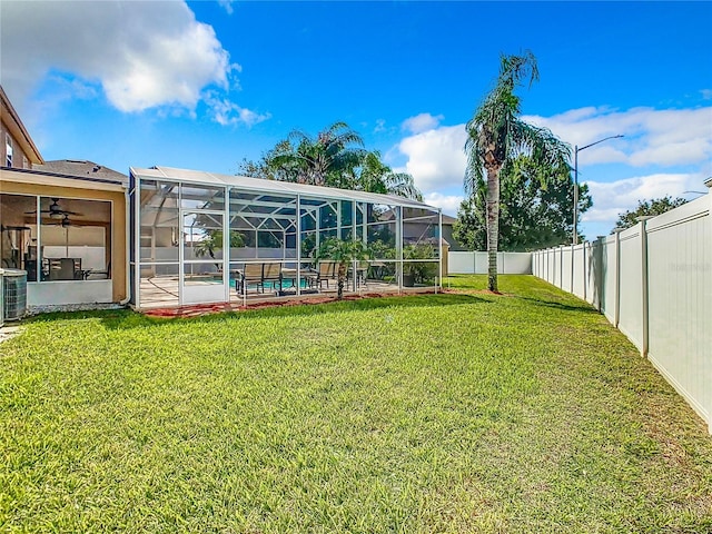 view of yard with a swimming pool, central AC unit, ceiling fan, glass enclosure, and a patio area