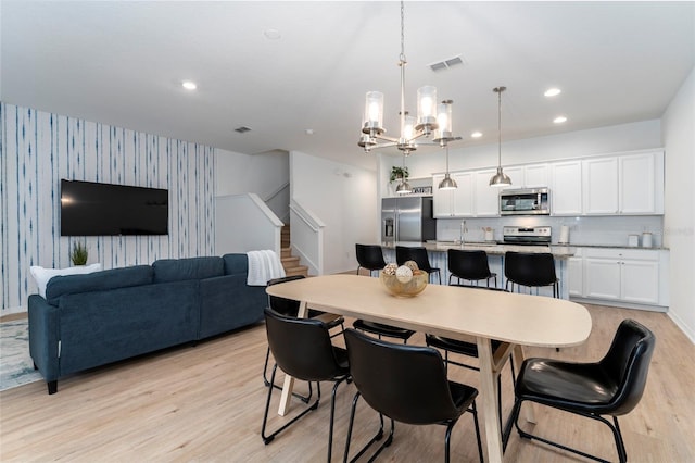 dining area with light hardwood / wood-style flooring and a notable chandelier