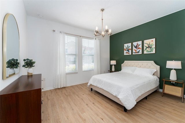 bedroom with light hardwood / wood-style flooring and an inviting chandelier