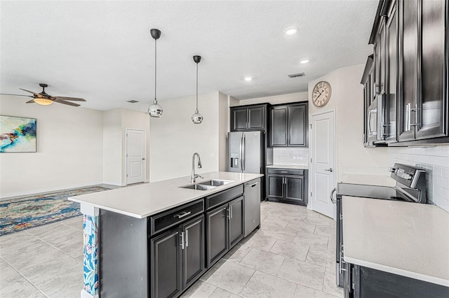 kitchen with hanging light fixtures, backsplash, a center island with sink, sink, and appliances with stainless steel finishes