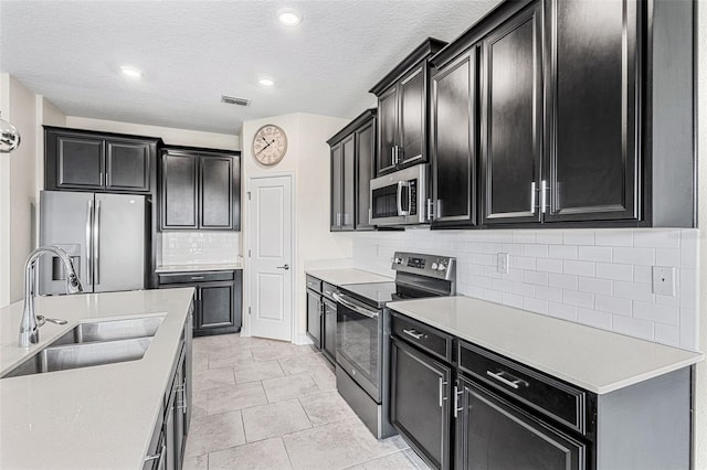 kitchen with light tile patterned floors, backsplash, a textured ceiling, sink, and stainless steel appliances