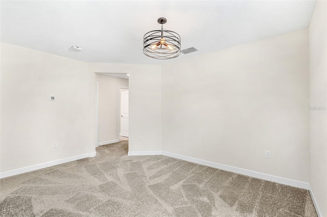 empty room featuring a textured ceiling and light colored carpet