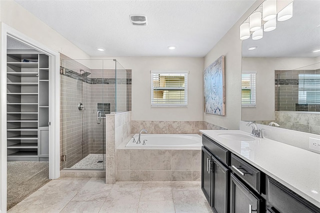 bathroom featuring vanity, a textured ceiling, plenty of natural light, and plus walk in shower