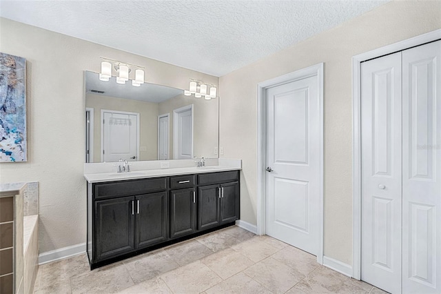 bathroom with vanity, a textured ceiling, and a bath