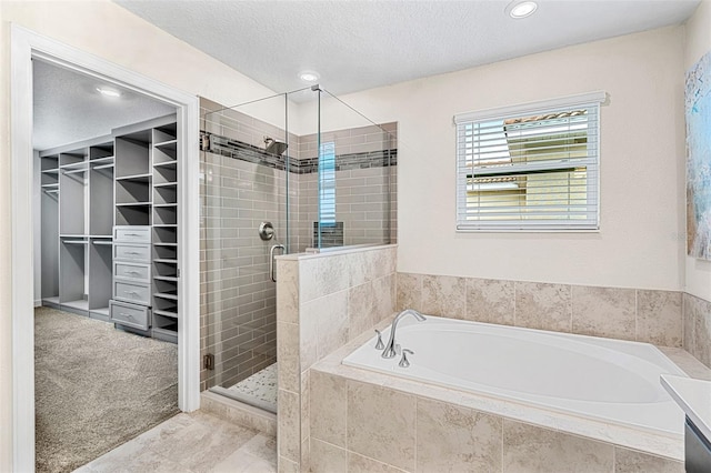 bathroom featuring a textured ceiling and separate shower and tub