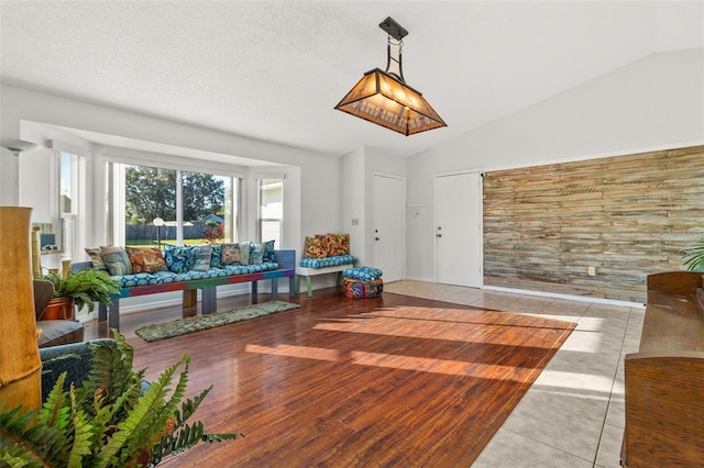 recreation room featuring a textured ceiling, light tile patterned flooring, and vaulted ceiling